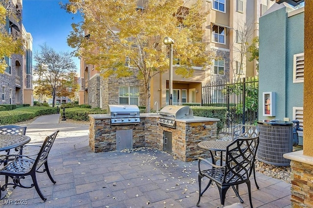 view of patio / terrace with central AC unit, grilling area, fence, and an outdoor kitchen