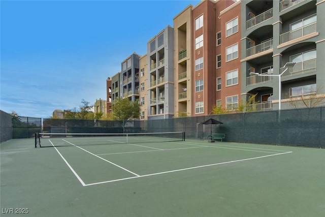 view of tennis court featuring community basketball court and fence