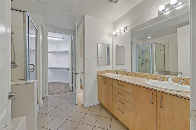 bathroom featuring a stall shower, a walk in closet, tile patterned flooring, and a sink