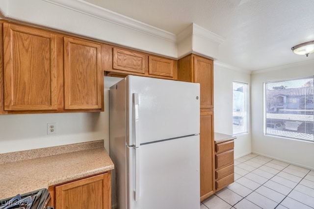 kitchen with light tile patterned floors, stove, white fridge, and crown molding