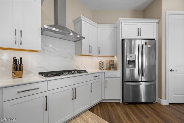 kitchen with decorative backsplash, white cabinets, wall chimney range hood, and appliances with stainless steel finishes