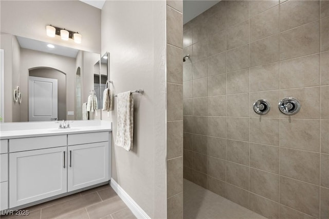 bathroom featuring tiled shower and vanity