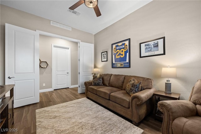 living room with ceiling fan and dark wood-type flooring