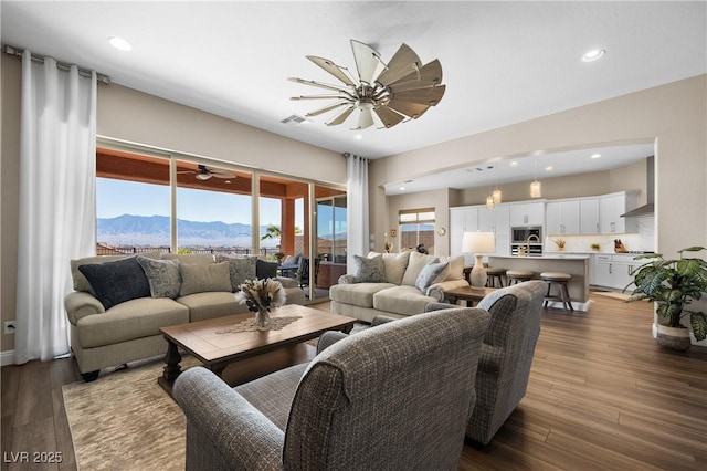 living room featuring a mountain view, light hardwood / wood-style floors, plenty of natural light, and ceiling fan