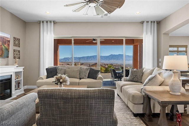 living room with a mountain view, hardwood / wood-style floors, and ceiling fan