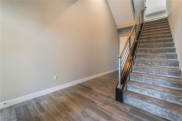 stairway featuring high vaulted ceiling and wood-type flooring