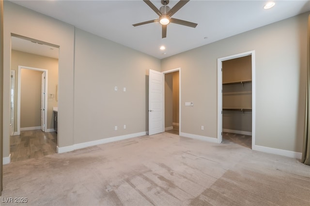 unfurnished bedroom with a spacious closet, ceiling fan, a closet, and light colored carpet