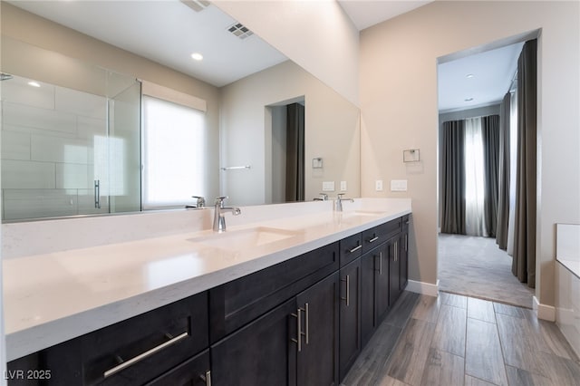 bathroom with a healthy amount of sunlight, walk in shower, and vanity