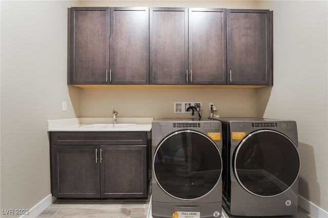 clothes washing area with washer and clothes dryer, sink, and cabinets