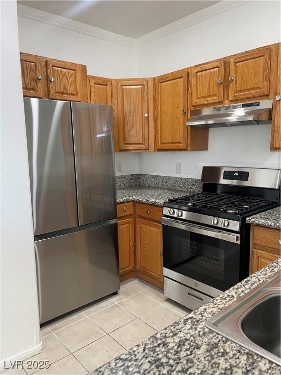 kitchen featuring sink, crown molding, dark stone countertops, light tile patterned floors, and stainless steel appliances