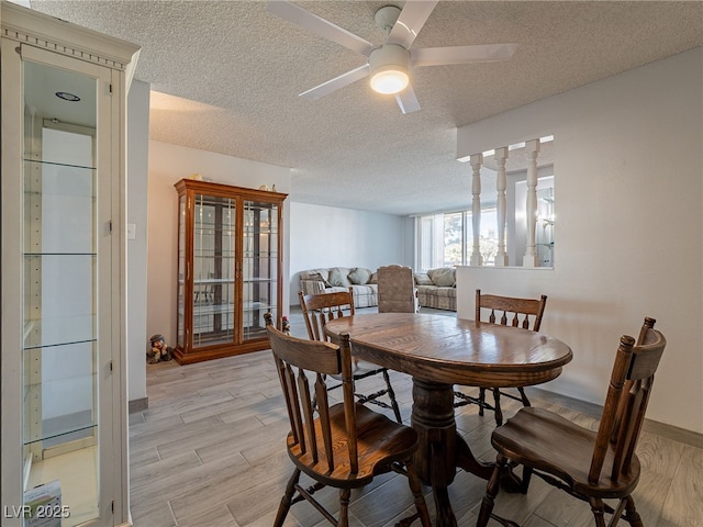 dining room featuring a textured ceiling, ceiling fan, light wood finished floors, and baseboards