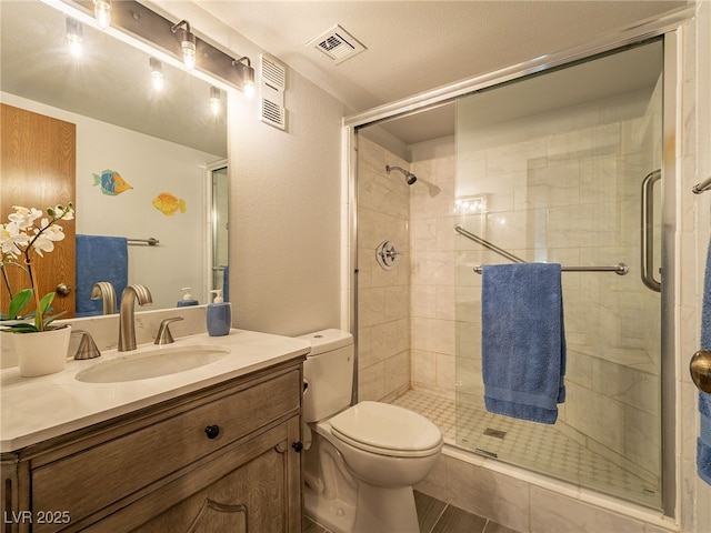 full bath with toilet, a stall shower, vanity, and visible vents