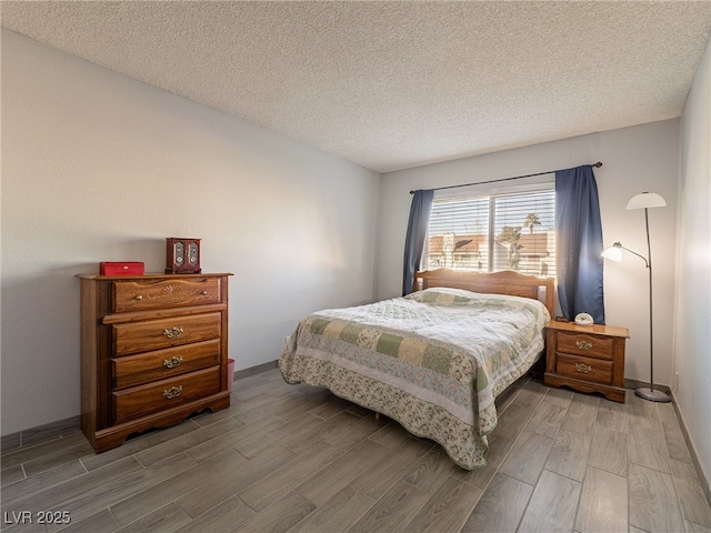 bedroom with wood finish floors, a textured ceiling, and baseboards