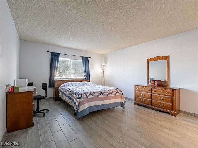 bedroom with light wood-style floors and a textured ceiling