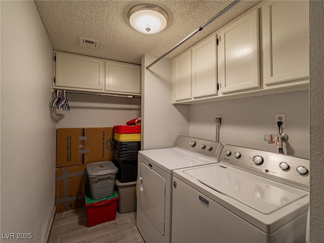 laundry area featuring cabinet space, visible vents, wood tiled floor, a textured ceiling, and washer and dryer