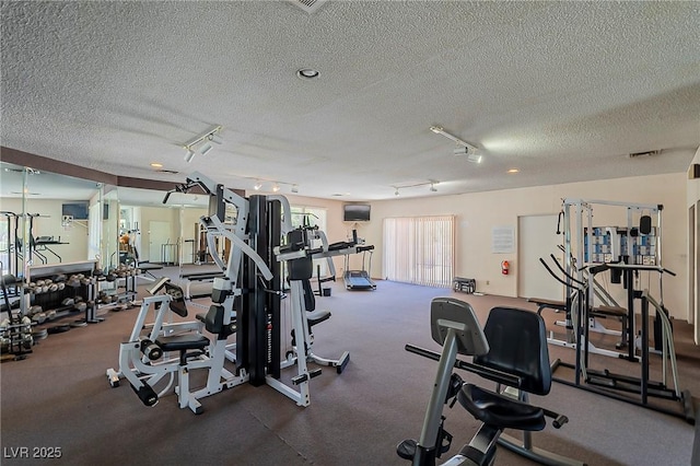 exercise room featuring a textured ceiling and rail lighting