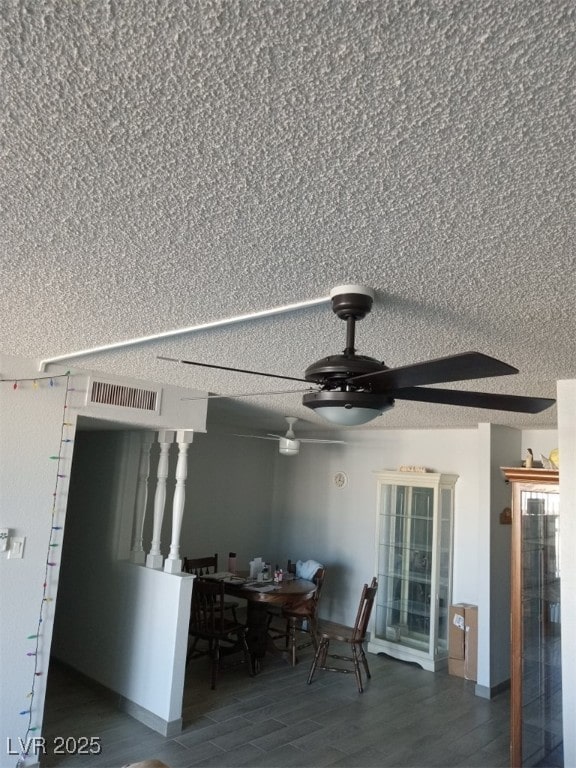 interior space featuring ceiling fan, a textured ceiling, visible vents, and wood finished floors