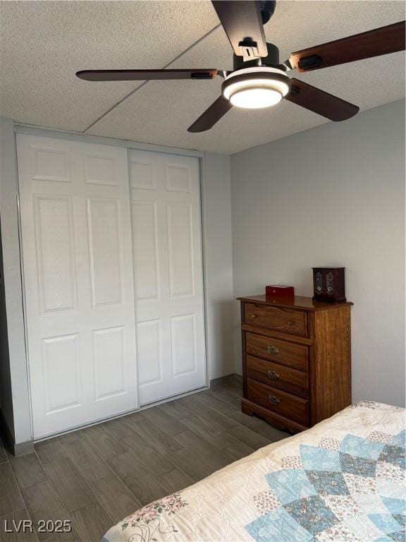 bedroom with a textured ceiling, a closet, a ceiling fan, and wood finished floors