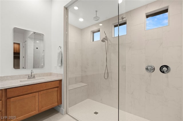 bathroom with tiled shower and vanity