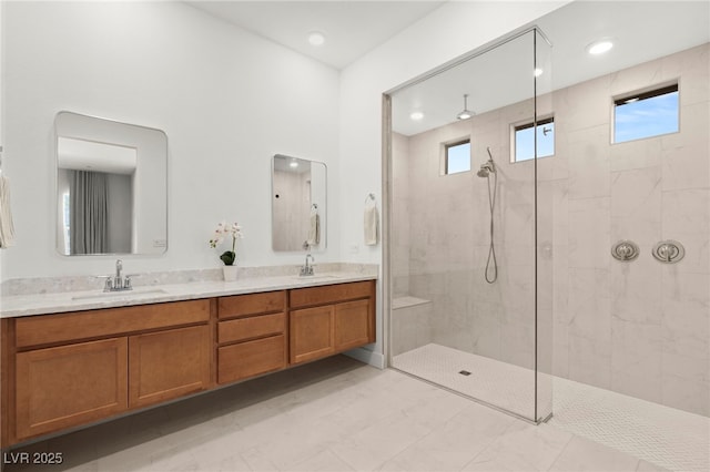 bathroom featuring tiled shower, vanity, and plenty of natural light