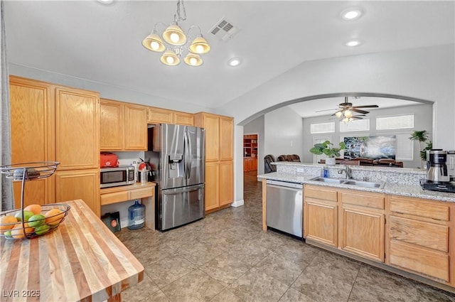 kitchen with lofted ceiling, sink, hanging light fixtures, light brown cabinets, and stainless steel appliances