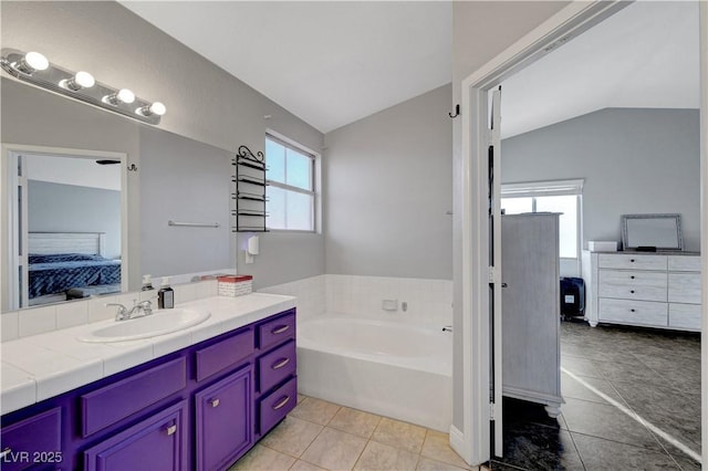 bathroom with tile patterned flooring, vanity, lofted ceiling, and a bathtub