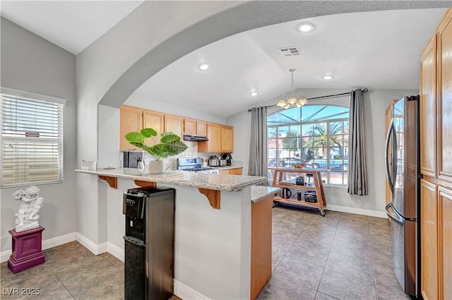 kitchen with appliances with stainless steel finishes, pendant lighting, a kitchen breakfast bar, kitchen peninsula, and light brown cabinets