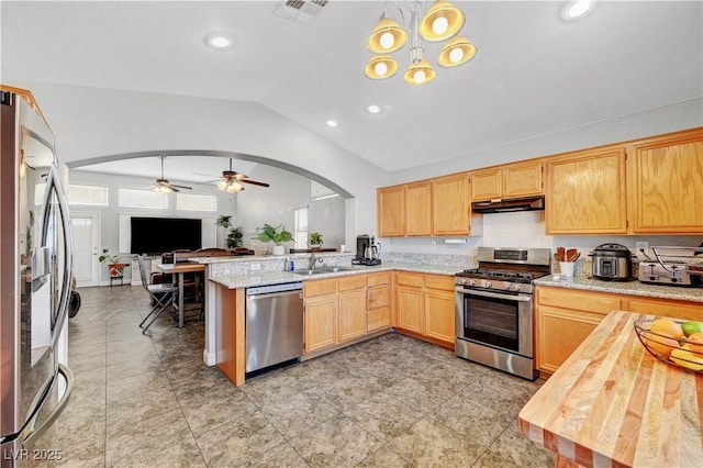 kitchen with sink, stainless steel appliances, decorative light fixtures, vaulted ceiling, and kitchen peninsula