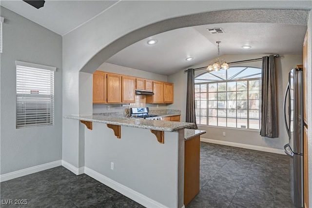 kitchen with lofted ceiling, a breakfast bar, hanging light fixtures, stainless steel appliances, and light stone countertops