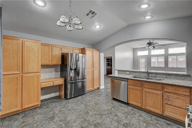 kitchen featuring vaulted ceiling, appliances with stainless steel finishes, ceiling fan with notable chandelier, sink, and light stone countertops