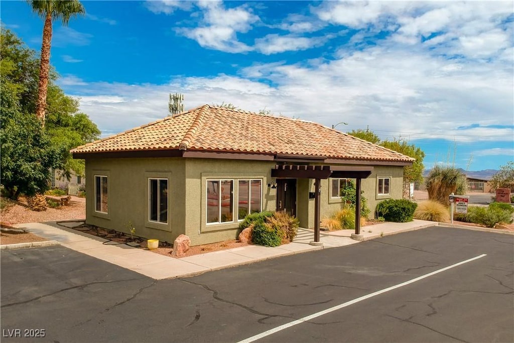 view of front of property with uncovered parking, a tile roof, and stucco siding