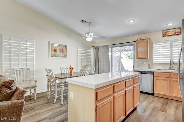 kitchen featuring a center island, sink, light hardwood / wood-style flooring, stainless steel dishwasher, and tile countertops