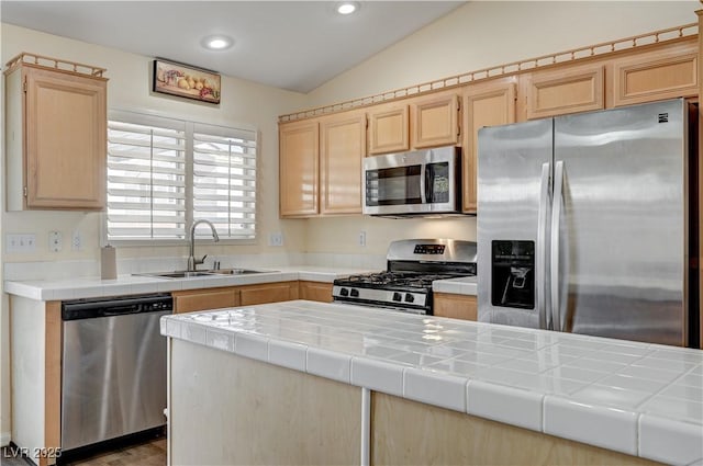 kitchen featuring tile countertops, stainless steel appliances, lofted ceiling, and sink