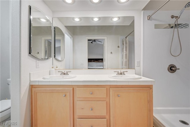 bathroom featuring vanity, toilet, walk in shower, and ceiling fan