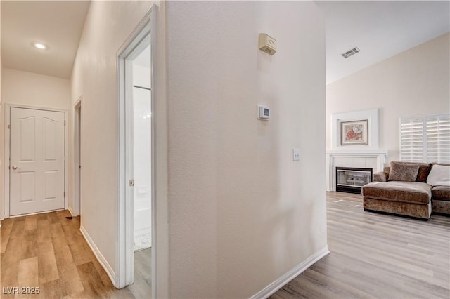 hallway with light hardwood / wood-style floors and lofted ceiling