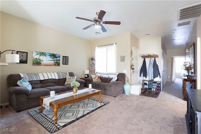 living area with carpet, visible vents, and ceiling fan