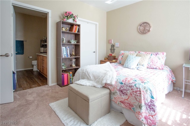 carpeted bedroom with connected bathroom and baseboards