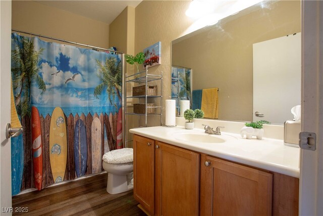 bathroom with toilet, curtained shower, vanity, and wood finished floors