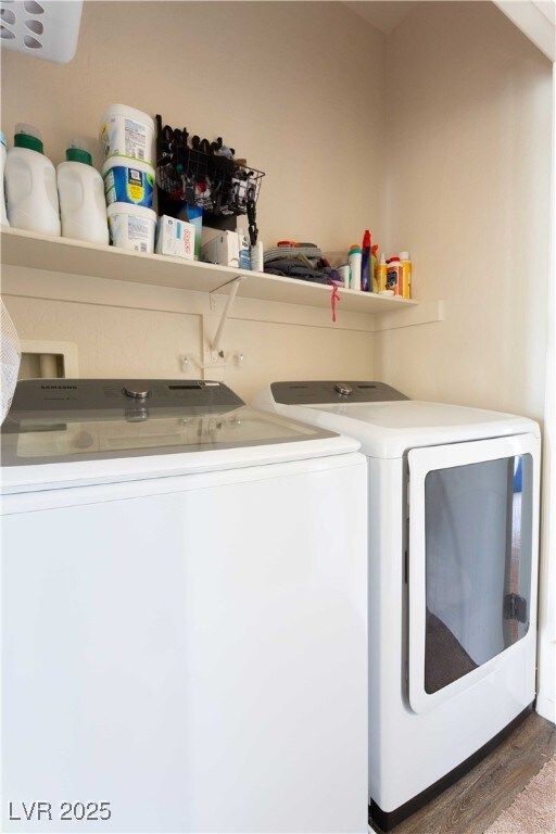 washroom featuring laundry area, wood finished floors, and separate washer and dryer