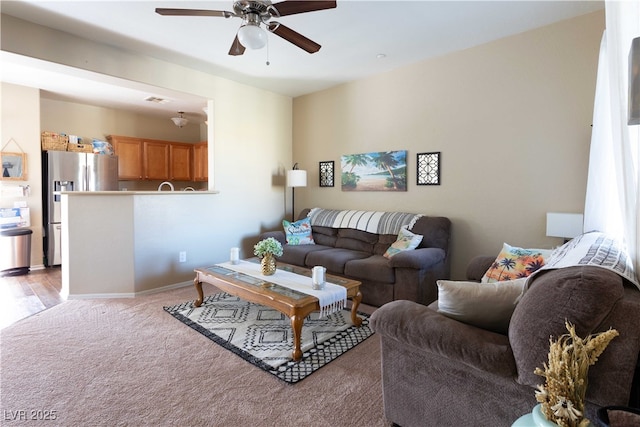 living area featuring carpet flooring, a ceiling fan, and baseboards