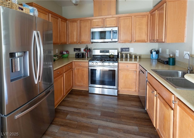 kitchen featuring a sink, stainless steel appliances, dark wood finished floors, and light countertops