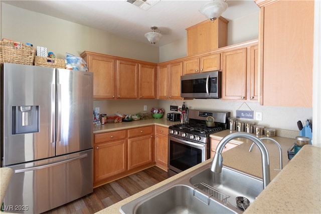 kitchen featuring a sink, stainless steel appliances, wood finished floors, and light countertops