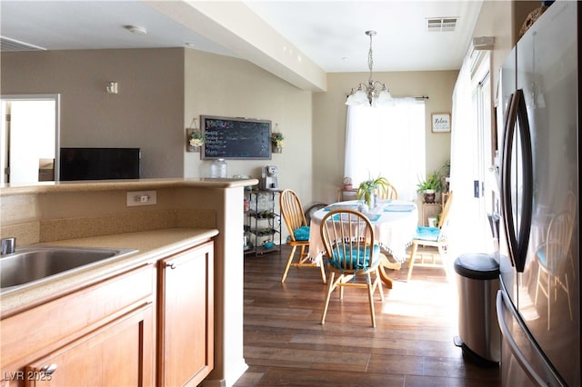 kitchen featuring visible vents, decorative light fixtures, dark wood-style floors, freestanding refrigerator, and light countertops