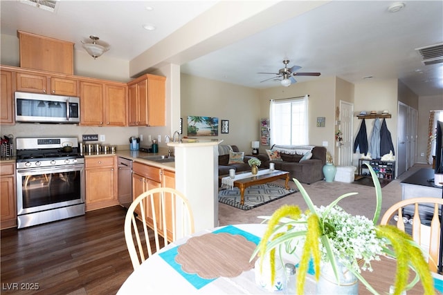 kitchen featuring visible vents, a sink, dark wood-type flooring, appliances with stainless steel finishes, and open floor plan