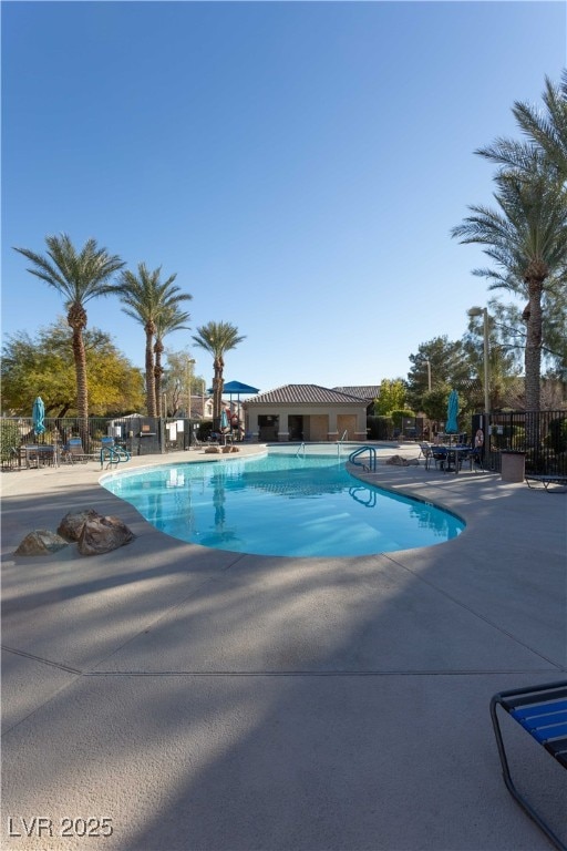 pool with a patio area and fence