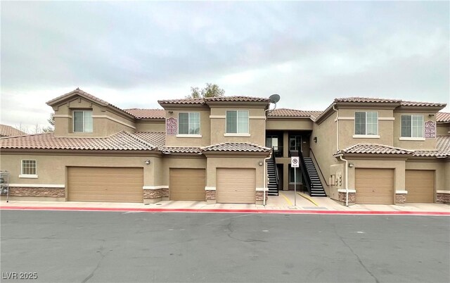 mediterranean / spanish home with stairway, a garage, stone siding, and stucco siding