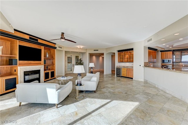 unfurnished living room featuring beverage cooler and ceiling fan