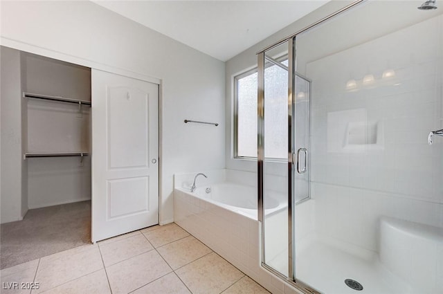 bathroom featuring a walk in closet, a stall shower, a garden tub, and tile patterned floors