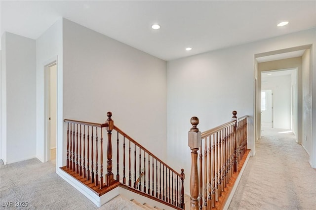 hall featuring carpet floors, recessed lighting, and an upstairs landing