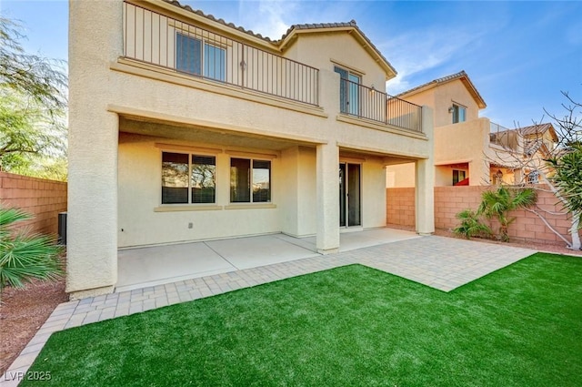 rear view of property featuring a balcony, a patio area, fence, and stucco siding